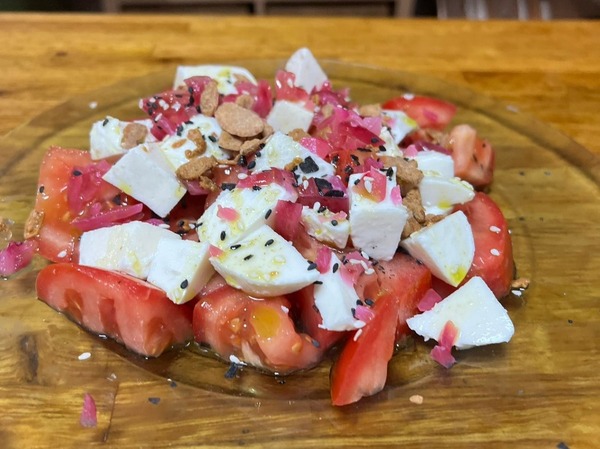 Ensalada de mozarella y tomate fresco con aceite de albahaca,crocanti de almendra y cebolla encurtida