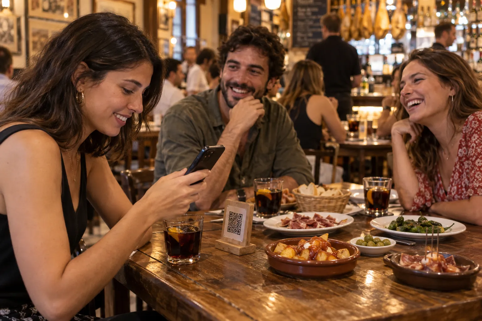 Amigos en un bar de tapas escanean con el móvil el código QR de la carta
